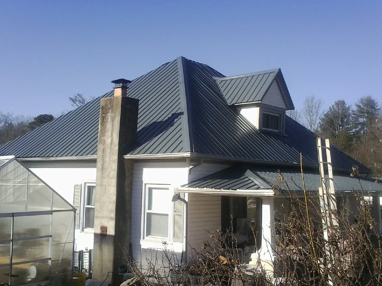 Dark blue standing seam metal roof on a white farmhouse with dormer — Slate & Tile Roof Repair by Roofing Brothers in Cross Plains