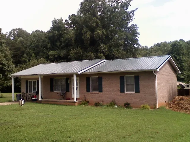 Gray metal roof on a brick ranch house with a side carport in Cross Plains