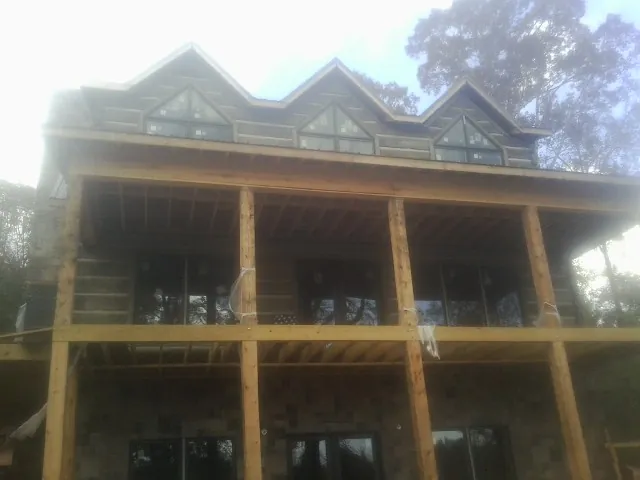 Dormers and porch framing on a large log home under construction — Roof Coating work by our crew in Cross Plains