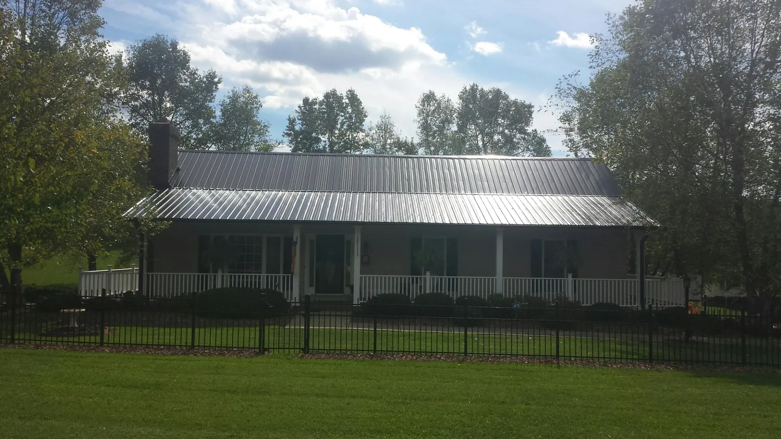 Gray metal roof on a brick ranch with a full width front porch — Gutter Guard Installation work by our crew in Cross Plains