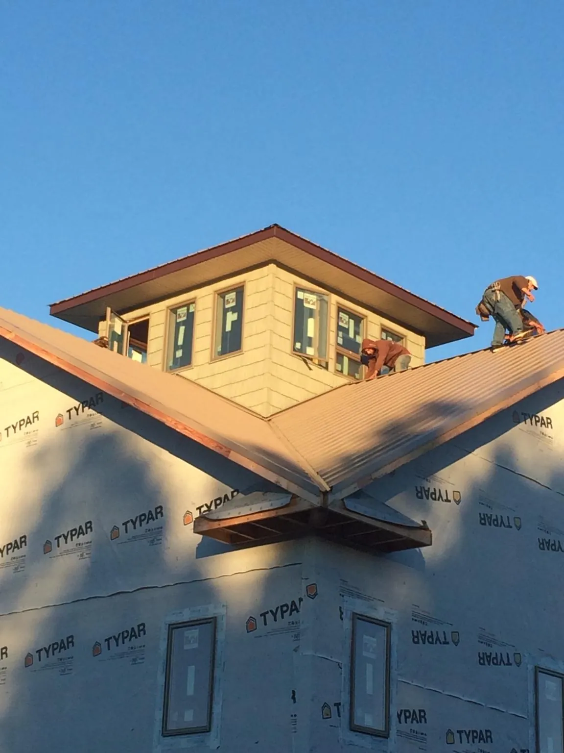 Roofers working around a rooftop cupola on a new metal roof at sunset — Roof Waterproofing in Cross Plains by Roofing Brothers
